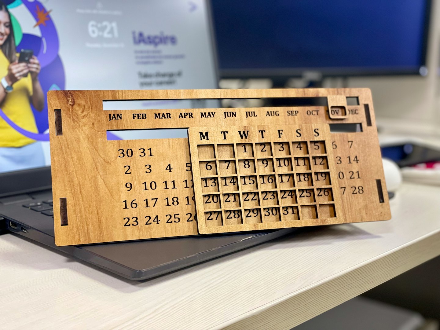 Wooden perpetual calendar sitting on an open laptop.