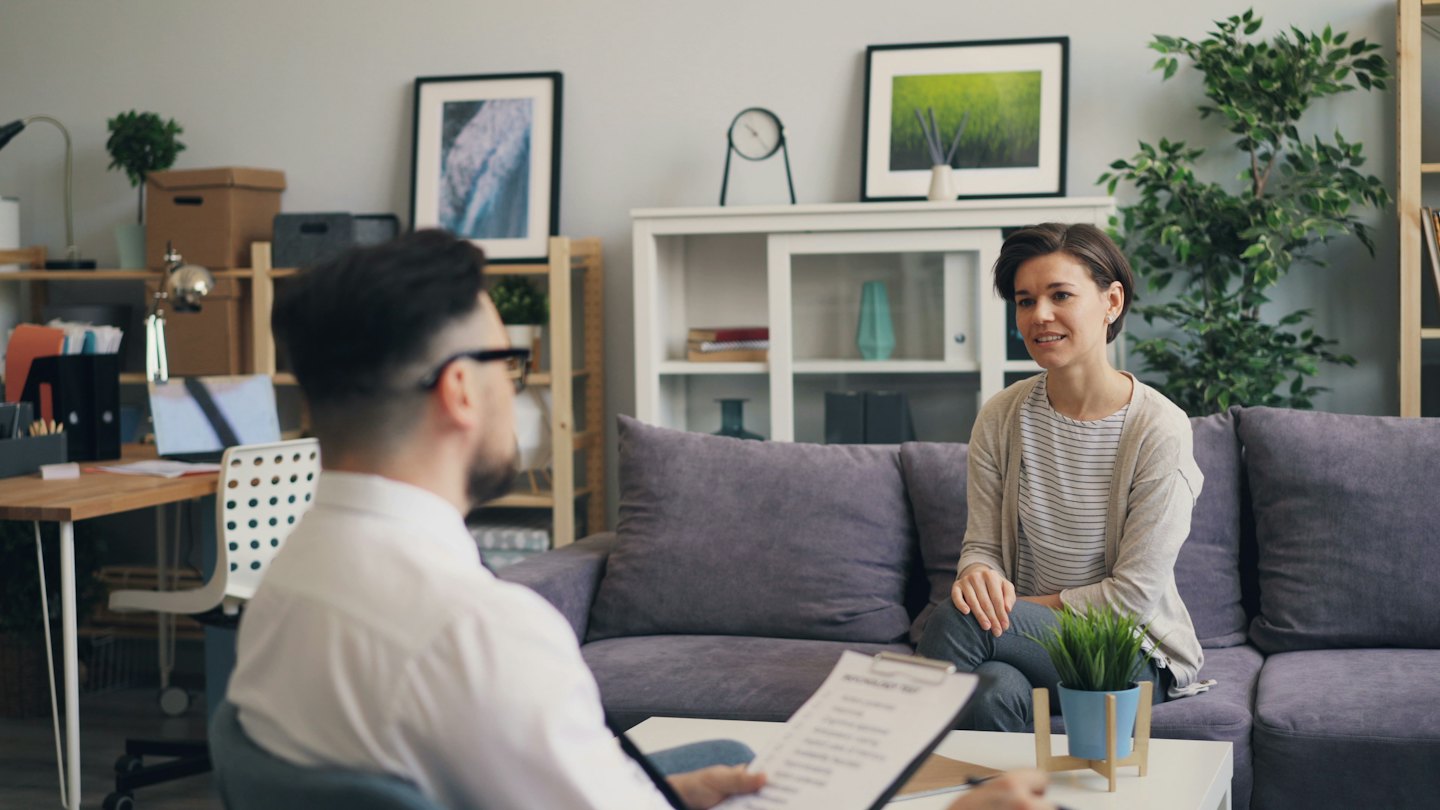 Therapist taking notes during a counseling session in an office.
